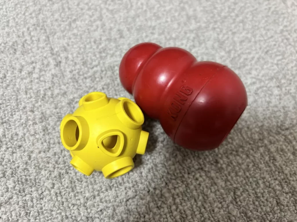 犬のお留守番中の暇つぶしや知育に大活躍するゴム製の赤いコングと黄色いおやつボール玩具