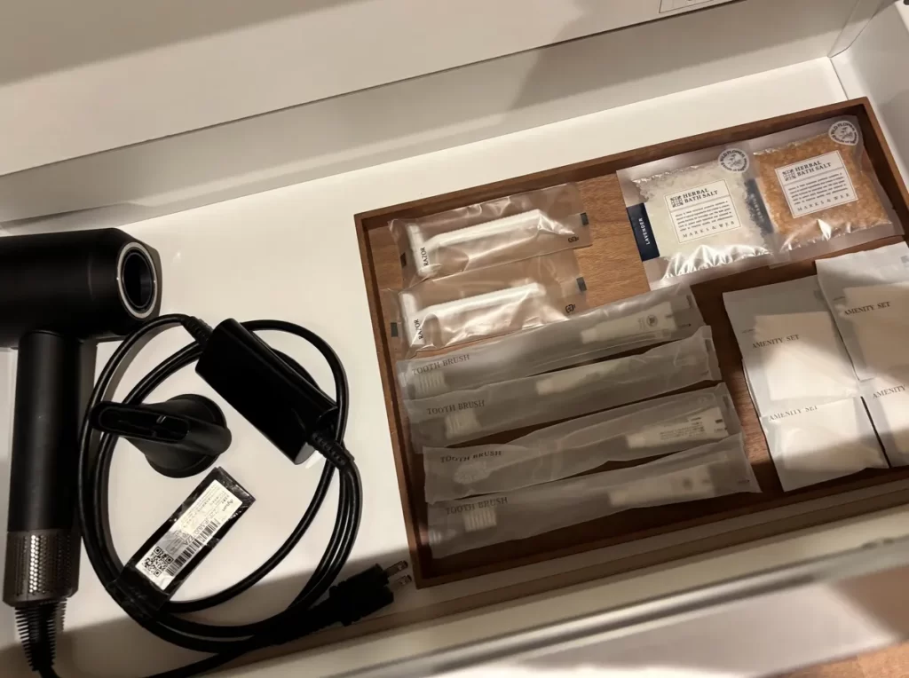 アメニティトレイにきれいに並んだ歯ブラシやカミソリなどの備品とダイソンの黒い高級ヘアドライヤー